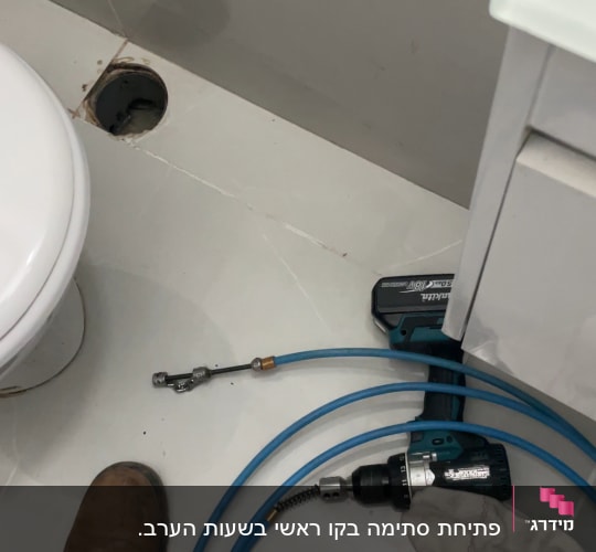 כלי עבודה וצינור ליד אסלה בחדר אמבטיה
